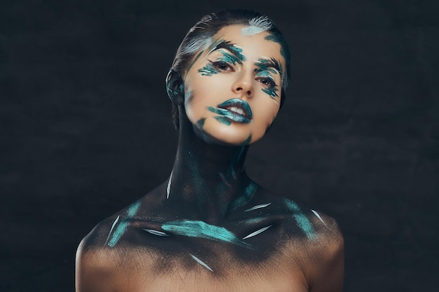 Young beauty girl with creative make-up. Blue and black shadows painted on her face. Conceptual idea.