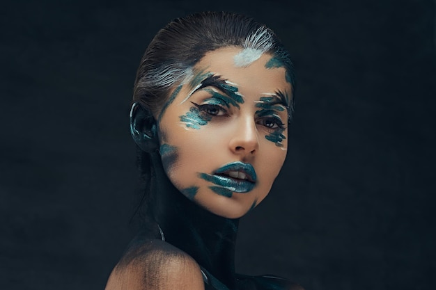 Free photo young beauty girl with creative make-up. blue and black shadows painted on her face. conceptual idea.