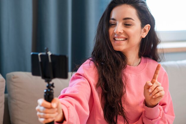 Young blogger holding her smartphone and finger up