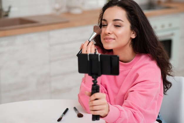 Young blogger recording herself and putting make up on