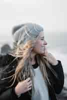 Free photo young blonde female with a hat having fun on the beach in a windy weather