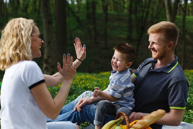 Young blonde mother plays with her son during a picnic in the park