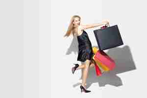 Free photo young blonde woman in black dress shopping on white background. attractive caucasian female model.