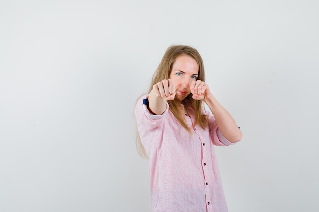 Free photo young blonde woman in a casual pink shirt prepared to fight