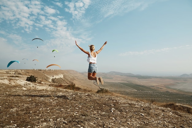 Free Photo young blonde woman jumping on top of hill