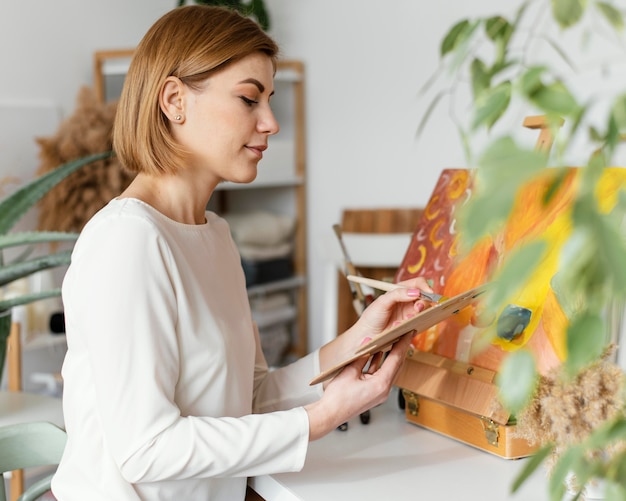 Free photo young blonde woman painting with acrylics