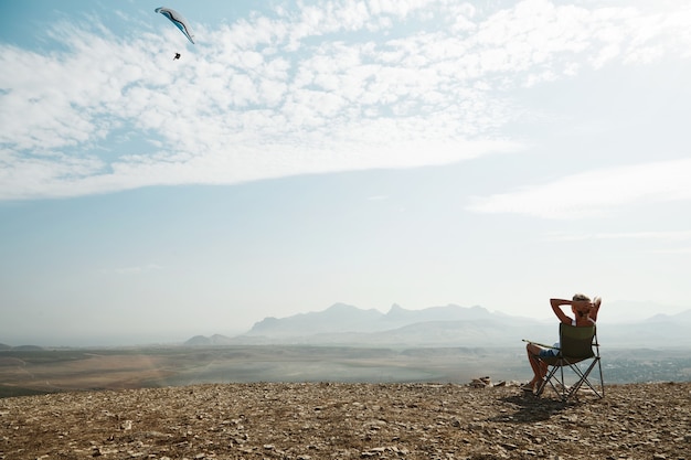 Free photo young blonde woman sitting on top of hill