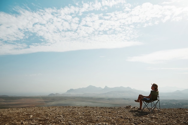 Young blonde woman sitting on top of hill