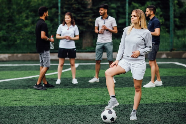 Free photo young, blonde woman smiling and happy, with soccer ball, excited to play a game