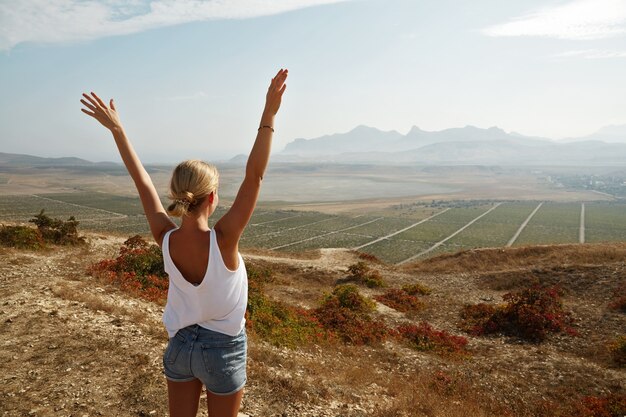 Young blonde woman standing on top of hill