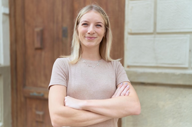 Young blonde woman standing with arms crossed gesture at street