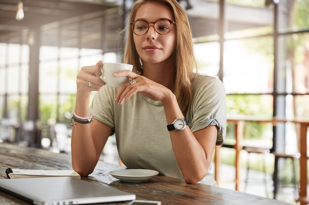 Young blonde woman with glasses in cafe