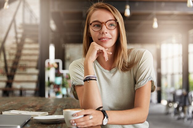 Young blonde woman with glasses in cafe