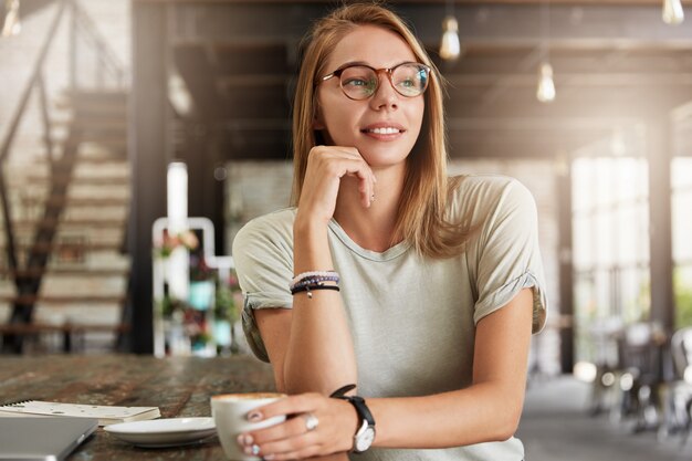 Young blonde woman with glasses in cafe