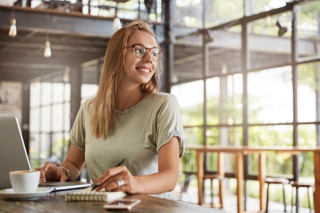 Young blonde woman with glasses in cafe