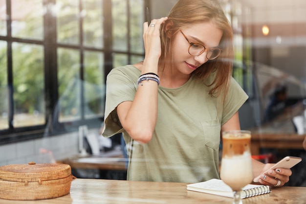 Young blonde woman with glasses in cafe