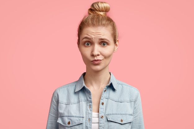 Free photo young blonde woman with hair in bun and wearing denim jacket