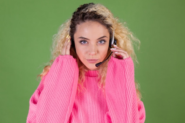 Free photo young blonde woman with long curly hair in pink sweater on green