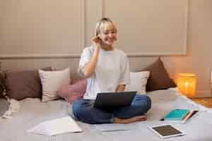 Free photo young blonde woman working from home on her laptop