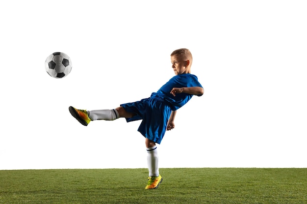 Young boy as a soccer or football player in sportwear making a feint or a kick with the ball for a goal on white.