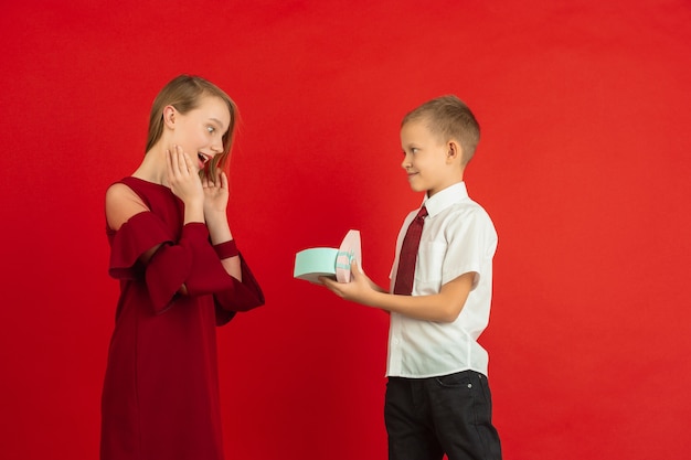 Young boy giving heart-shaped box to a girl