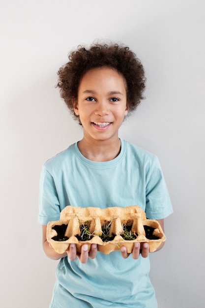 Free photo young boy holding greenery planted in upcycled pot