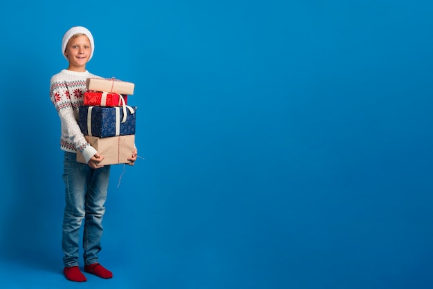 Free photo young boy holding pile of presents