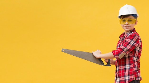 Free photo young boy holding saw tool copy space