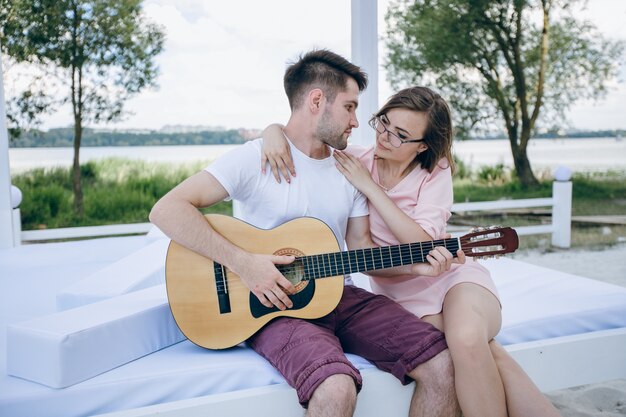 Young boy playing the guitar to his girlfriend while she hugs him