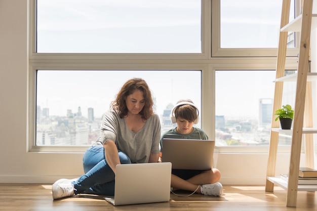 Young boy playing on laptop next to mom