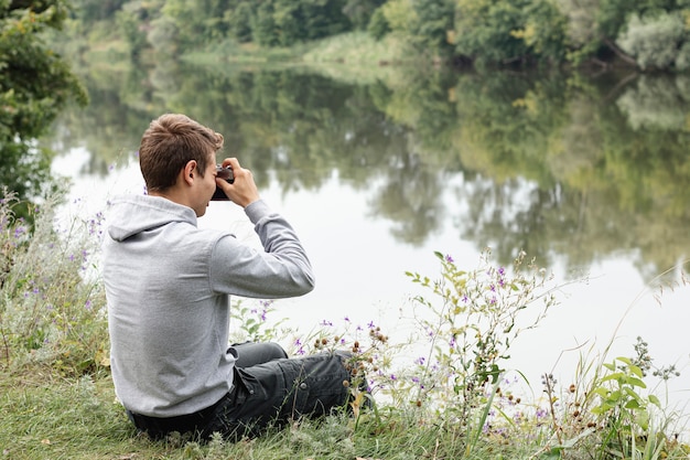 Free photo young boy taking pictures near lake