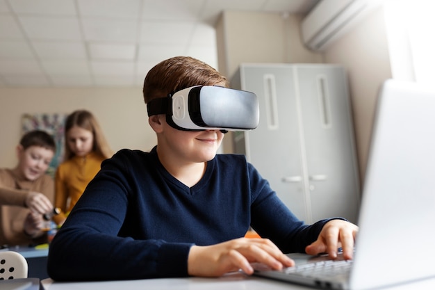 Free photo young boy using a laptop and vr glasses