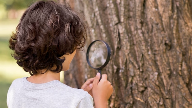 Free photo young boy with magnifier