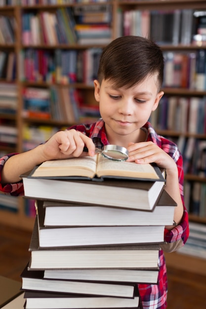 Young boy with stack of books reading