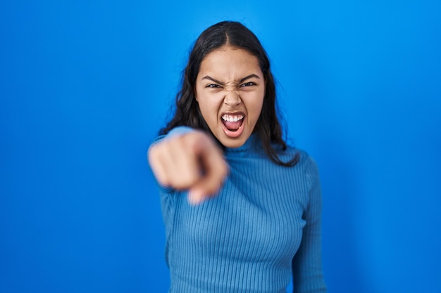 Young brazilian woman standing over blue isolated background pointing displeased and frustrated to the camera, angry and furious with you