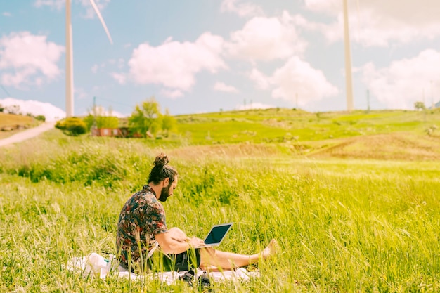 Free photo young brunet male sitting with laptop in rural