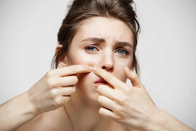 Free Photo young brunette girl displeased of her problem acne face skin over white background. health cosmetology and skincare.