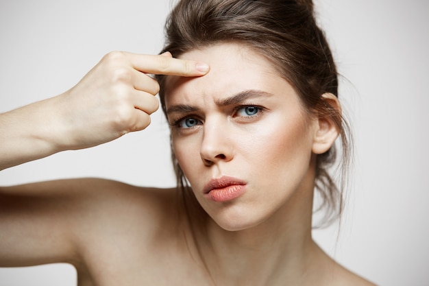 Free Photo young brunette girl displeased of her problem acne face skin over white background. health cosmetology and skincare.