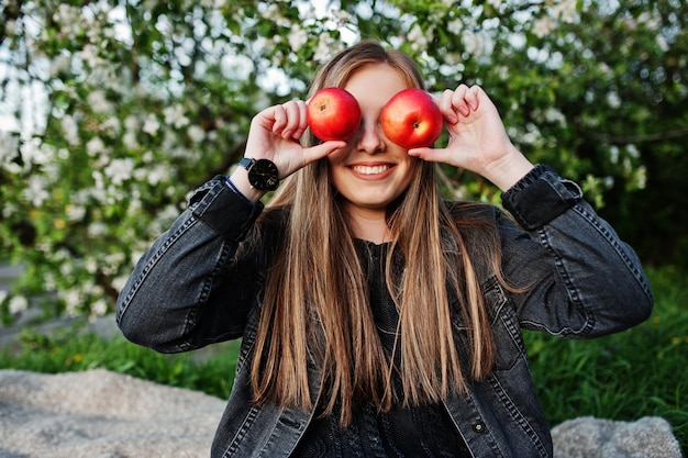 Free Photo young brunette girl at jeans sitting on plaid against spring blossom tree and show apple eyes