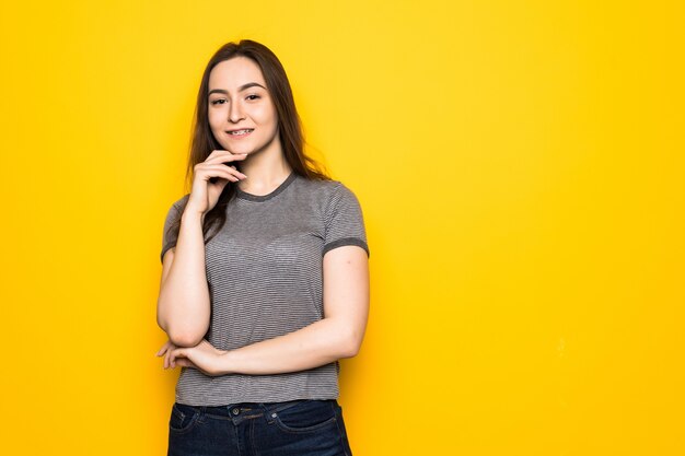 Young brunette girl standing on yellow wall.