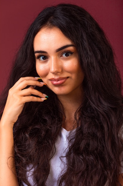 Young brunette girl with long and curly hairs promoting autumn makeup style. 