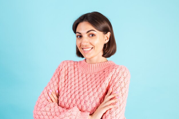 Young brunette in pink sweater isolated on blue wall