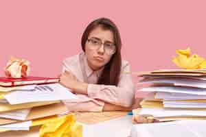 Free photo young brunette student sitting at desk with books