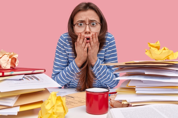 Young brunette student sitting at desk with books