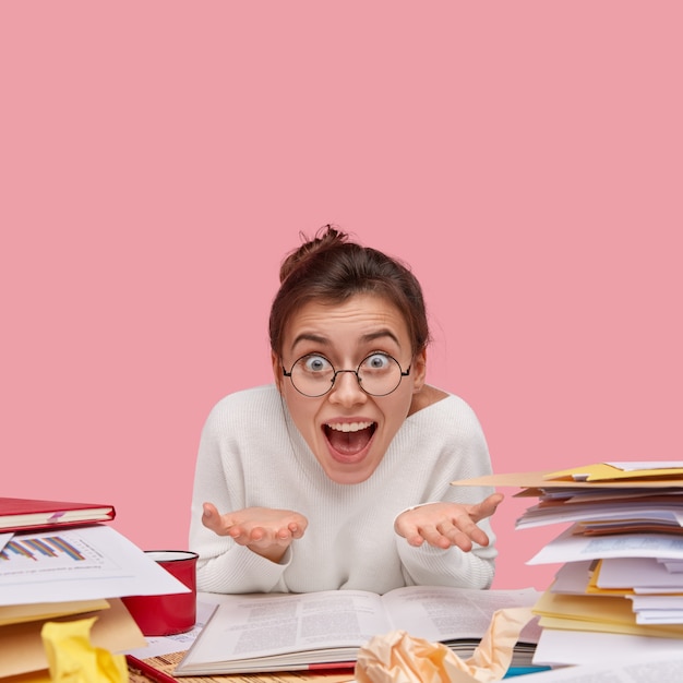 Young brunette student sitting at desk with books