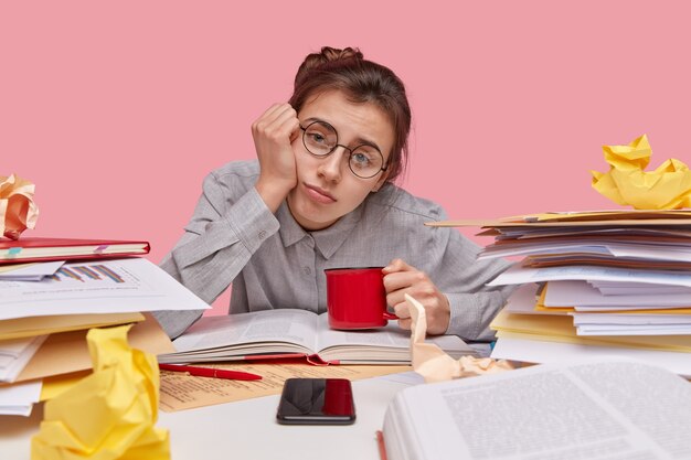 Young brunette student sitting at desk with books