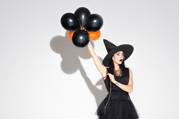 Free photo young brunette woman in black hat and costume on white