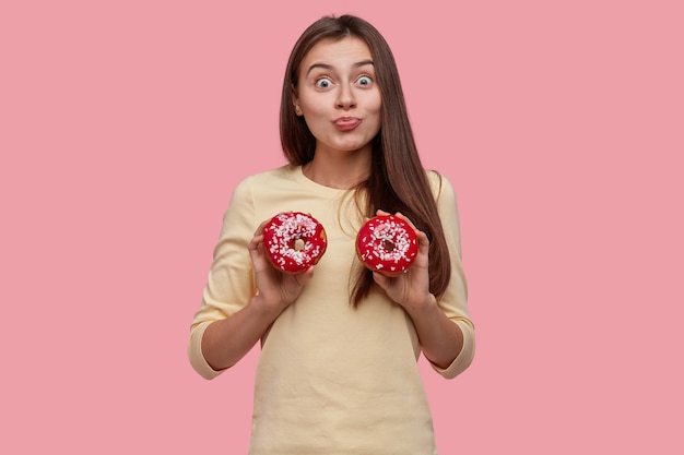 Free photo young brunette woman holding tasty donuts