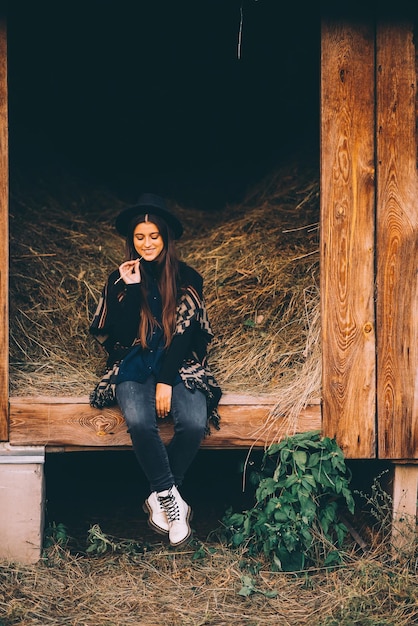 Young brunette woman sitting at the barn Country style