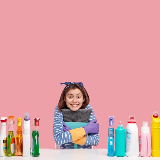 Young brunette woman sitting next to cleaning products